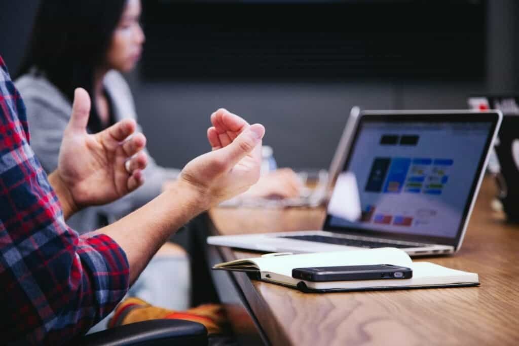 Business owner explaining their needs to a website designer during a planning meeting with a laptop
